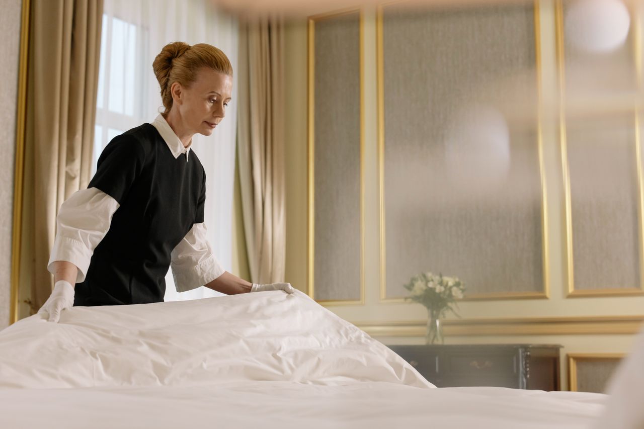 why-choose-us-03 A professional housekeeper makes a bed in a luxurious hotel room.